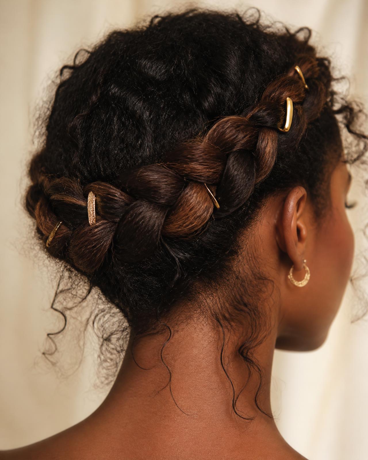 Crown braid wrapped at the nape with gold pins